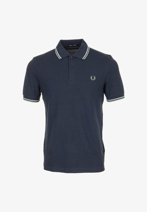 Polo blu navy a maniche corte, con abbottonatura a due bottoni, colletto e bordi delle maniche a righe bianche, e piccolo logo della corona d'alloro sul petto.