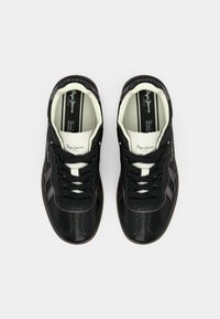 Μαύρα αθλητικά παπούτσια με υφή στην επιφάνεια, λευκά κορδόνια, αντίθετες σκούρες ρίγες και λογότυπο στο πλάι. Στρογγυλεμένη μύτη.