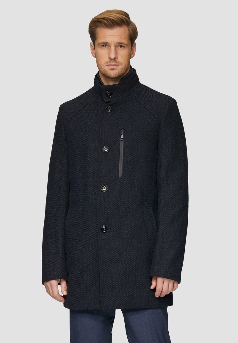 Donkerblauwe jas van een wollen mix met een hoge kraag, vijf knopen aan de voorkant, een zak met rits en zijzakken; gestructureerde stof met een subtiel patroon.