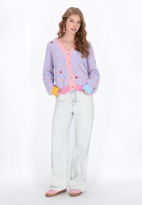 Cardigan tricotat multicolor cu modele în formă de inimă; bază lavandă, margine roz și accente colorate. Purtați-l peste blugi deschiși și încălțăminte roz.