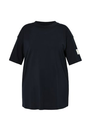 Černé oversized tričko s krátkými rukávy a kulatým výstřihem s malou bílou obdélníkovou nášivkou na levém rukávu.