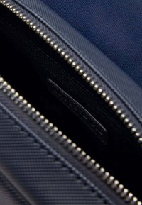 Sacchetto con zip di colore navy, con un esterno in tessuto testurizzato, dotato di una zip in tonalità argentata e di una piccola etichetta nera all'interno.