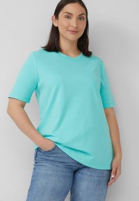 Licht turquoise T-shirt met korte mouwen en een ronde hals, gemaakt van zachte stof, gecombineerd met lichtblauwe denim jeans.