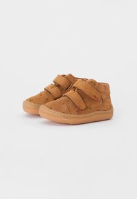 Braune Wildlederschuhe mit zwei Klettverschlüssen, ausgestattet mit einer Gummisohle und einem dezenten, mehrfarbigen Sprenkelmuster. Niedrig geschnittene Knöcheldesign.