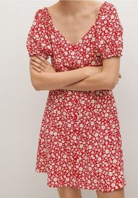 Rotes Kleid mit kurzen Puffärmeln, V-Ausschnitt und weißem Blumenmuster. Der Stoff ist leicht und das Design hat einen ausgestellten Rock.