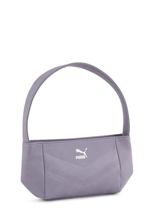 Mała jasnofioletowa torba na ramię Puma o kanciastym designie i szerokim pasku, spoczywająca na białej powierzchni.