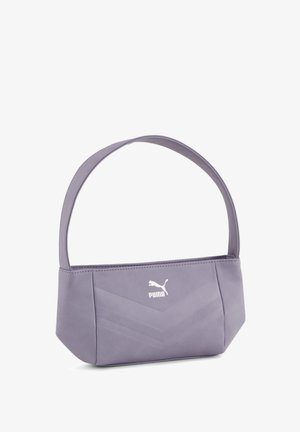 Pequeño bolso de hombro Puma de color púrpura claro con diseño angular y correa ancha, descansando sobre una superficie blanca.