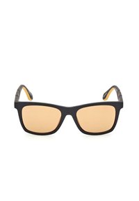 Occhiali da sole neri rettangolari con lenti ambra, finitura opaca e punte delle aste gialle in contrasto. Dettagli minimi sul telaio.