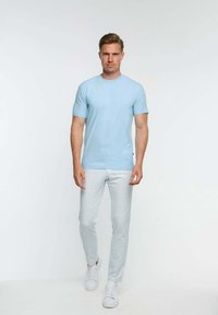 Világoskék pamut póló rövid ujjakkal, világosszürke, kockás slim-fit nadrággal és fehér sportcipővel párosítva. Egyszerű dizájn, díszítés nélkül.