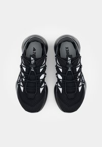 Black athletic shoes with a textured upper, featuring white accents and a lace closure system, designed for outdoor performance.