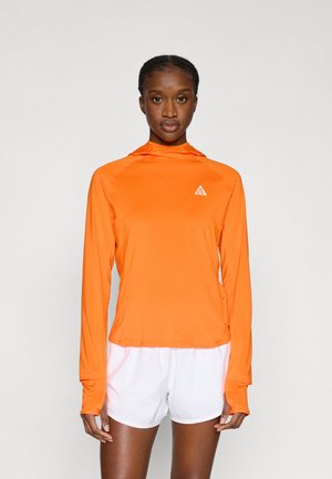 Tricou sport portocaliu cu mâneci lungi și glugă, realizat dintr-un material ușor, având un mic logo alb pe piept și detalii prelungite la manșete.