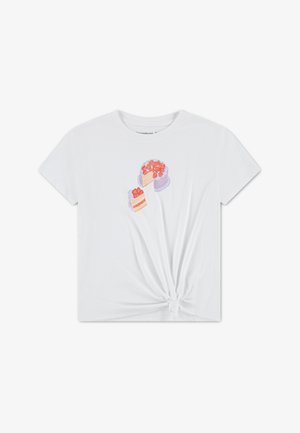 Bijela pamučna majica s čvorom na rubu. Sadrži šarene ilustracije dva kolača s jagodama na vrhu. Kratki rukavi i okrugli izrez.