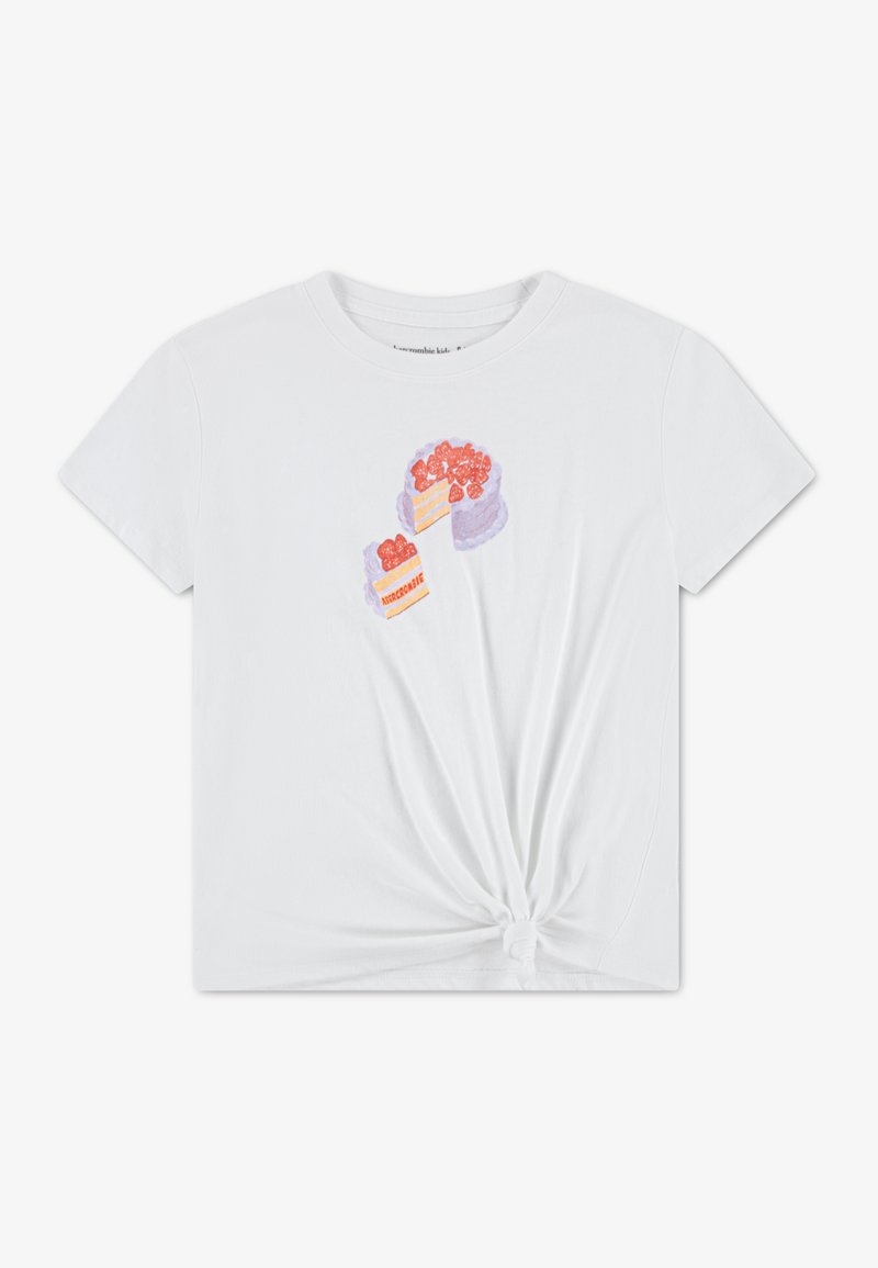 Άσπρο βαμβακερό t-shirt με κόμπο στο τελείωμα. Διακοσμημένο με πολύχρωμες απεικονίσεις δύο κέικ με φράουλες στην κορυφή. Κοντά μανίκια και στρογγυλή λαιμόκοψη.