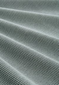 Textile featuring a zigzag pattern in black and light gray, showcasing a smooth texture with soft folds and subtle sheen.