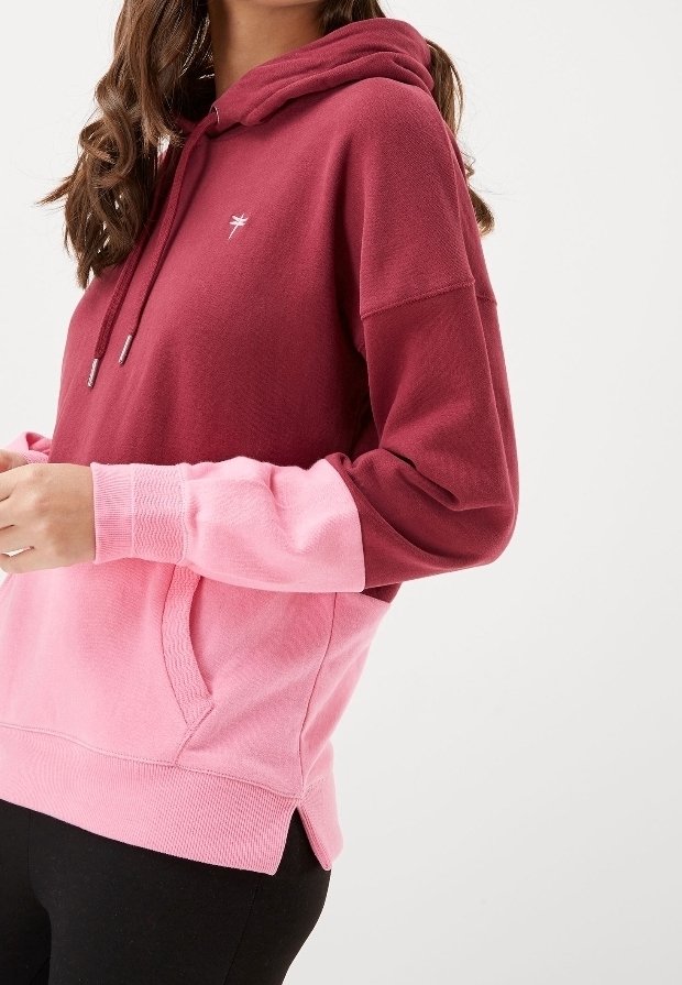Hooded sweatshirt with a maroon upper and pink lower. Features a front pocket, ribbed cuffs, and hem. Material appears soft and textured.