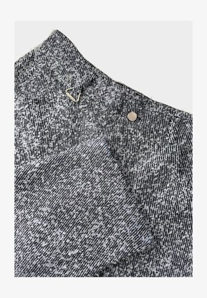 Gestructureerde, zwart-witte patroonkatoen met een zilveren driehoekaccent en een ronde metalen drukknoopdetail bij de tailleband.