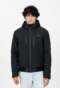 Zwarte zip-up jas met een capuchon, gemaakt van een gestructureerde stof, met twee verticale ritszakken en een geribde taille. Eenvoudig ontwerp zonder zichtbare patronen.