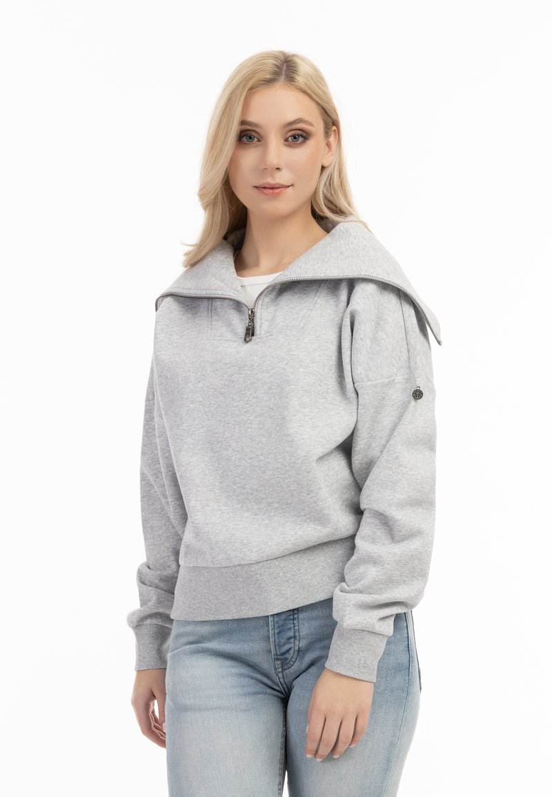 Grijze sweatvest met hoge kraag en een half-rits ontwerp. Voorzien van ribbelboorden en een ribbelzoom, subtiele textuur en details op de schoudernaad.