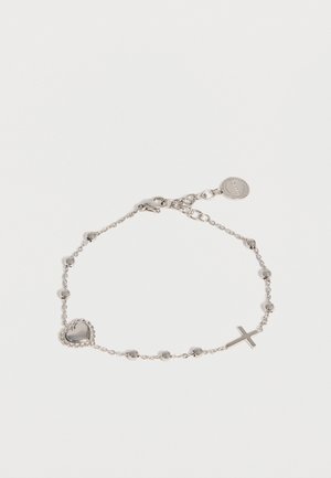 Bracelet chaîne en argent avec de petites perles, un pendentif en forme de cœur d’un côté, un pendentif en forme de croix de l’autre, et une étiquette ronde de marque près du fermoir.