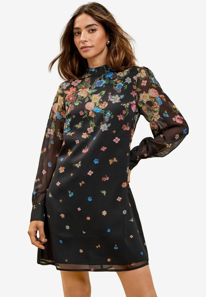 Rochie neagră cu flori, cu mâneci lungi și transparente, gât înalt și croi lejer. Este decorată cu modele florale colorate și fluturi pe parcursul întregii rochii.