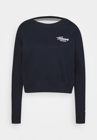 Mörkblå beskuren sweatshirt gjord av bomull. Har en rund halsringning, långa ärmar och en rosa broderad "Tommy Jeans"-logotyp på bröstet.