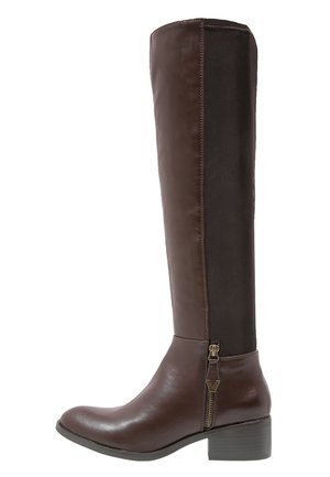 Brown knee-high boot featuring a glossy leather front and smooth fabric panel at the back, with a side zipper and a low stacked heel.