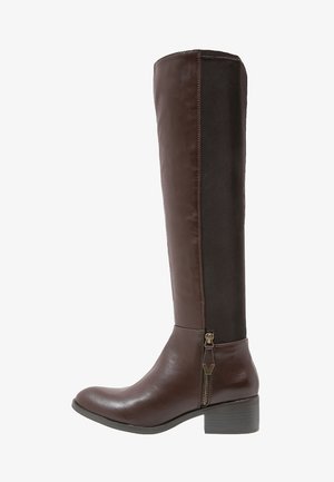 Brown knee-high boot featuring a glossy leather front and smooth fabric panel at the back, with a side zipper and a low stacked heel.