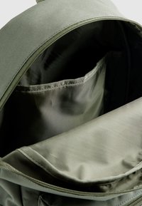 Ανοικτό σακίδιο πλάτης σε ελιά πράσινο που δείχνει ένα κενό κύριο διαμέρισμα με εσωτερική θήκη και μερικώς ανοιγμένο φερμουάρ.