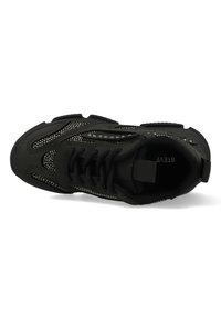 Baskets noires de sport avec une texture lisse, des panneaux en maille, des détails en studs métalliques, un système de laçage et un renfort au niveau du talon.