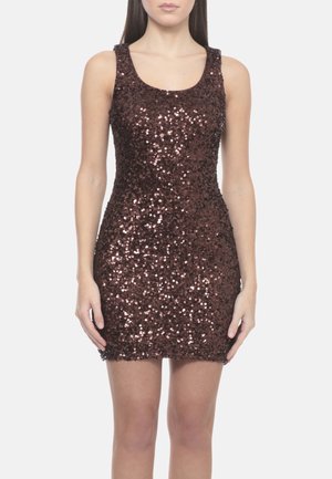 Donna che indossa un mini abito marrone scuro senza maniche coperto di paillettes lucenti, in piedi con le braccia rilassate lungo i fianchi davanti a uno sfondo chiaro.