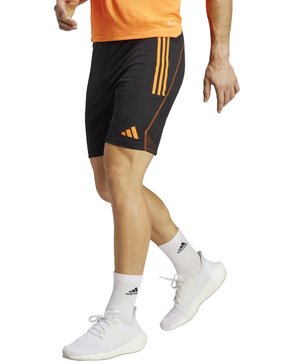 Zwarte sportshorts met oranje accenten, voorzien van drie zijstrepen, een meshpaneel en een elastische tailleband. Draagt witte sneakers.