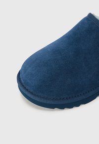 Chaussure à enfiler en daim bleu marine avec un bout rond et une surface texturée ; elle dispose d'une semelle en caoutchouc contrastante et de détails cousus.