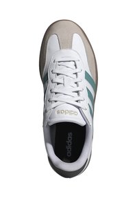 Zapatilla blanca con rayas en color teal, puntera de ante y parte superior de cuero texturizado. Presenta cordones blancos y un detalle del logo en dorado en la lengua.
