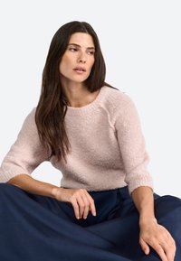 Pull en tricot rose clair avec une finition texturée et des manches trois-quarts, assorti d'une jupe bleu marine. Tissu doux et confortable.