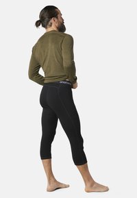 Men's thermal top in olive green and black capri pants with contrasting stitching, made from soft, breathable materials.