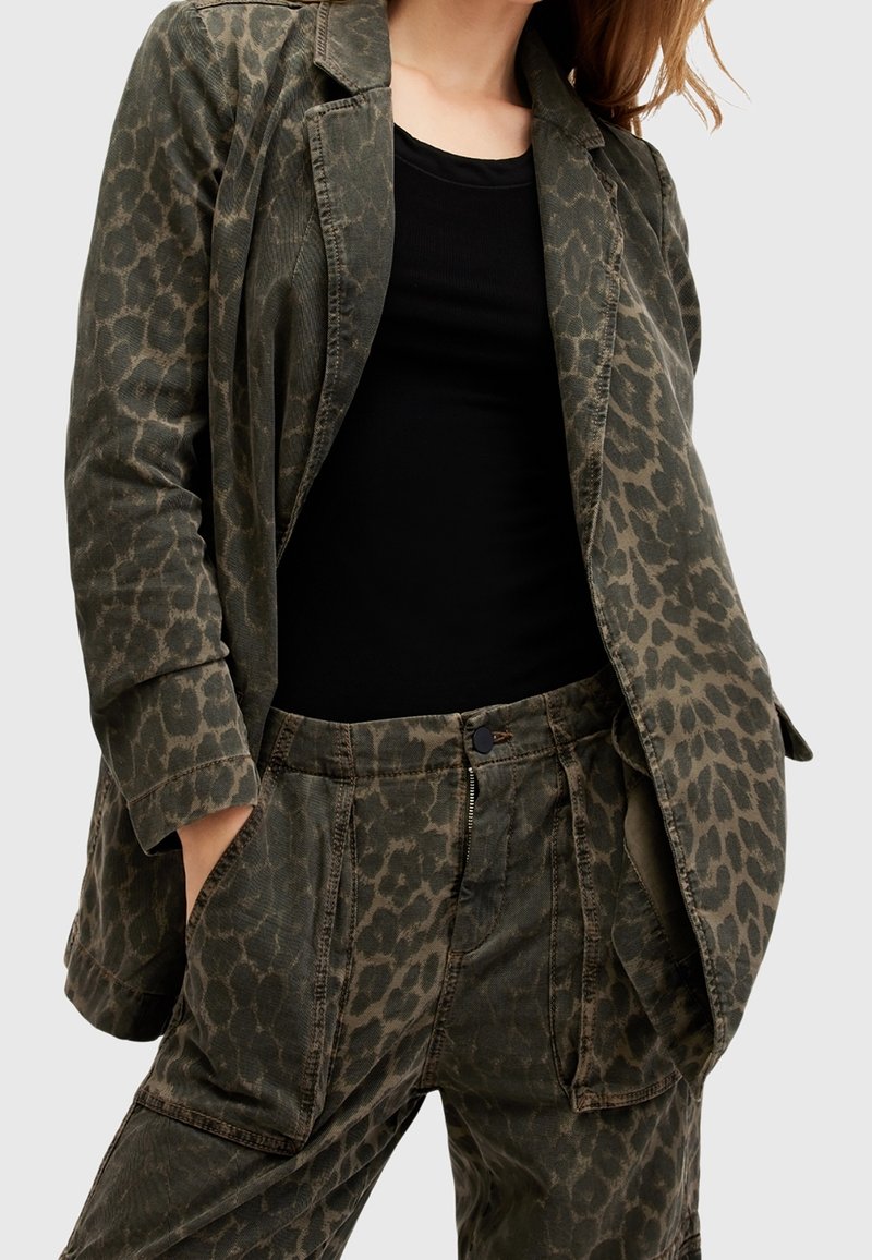 Olivgrön jacka med ett leopardmönster, tillverkad av en blandning av bomull. Har en skräddarsydd design och en avslappnad passform. Matchas med byxor i samma mönster.