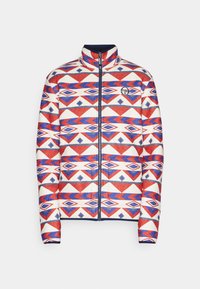 Fleecejack die een geometrisch patroon heeft in rood, blauw en wit, met een hoge kraag en een volledige rits, gemaakt van zacht, textuurmateriaal.