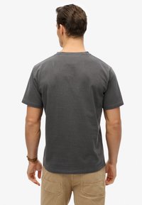 Grå bomuld T-shirt med rund hals, korte ærmer og løs pasform. Glat tekstur uden synlige mønstre eller detaljer.