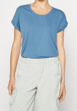 Niebieski t-shirt z krótkim rękawem i okrągłym dekoltem, wykonany z miękkiej tkaniny, noszony z jasnoszarymi spodniami cargo z bocznymi kieszeniami.