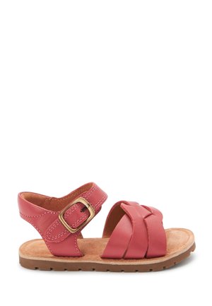 Sandale en cuir rose avec un design à brides croisées, boucle ajustable et semelle intérieure en daim marron. Elle possède une semelle extérieure en caoutchouc plate avec un détail texturé.