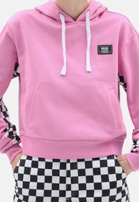 Sudadera con capucha rosa y cordones blancos, que presenta patrones a cuadros en blanco y negro en los laterales y un bolsillo frontal.