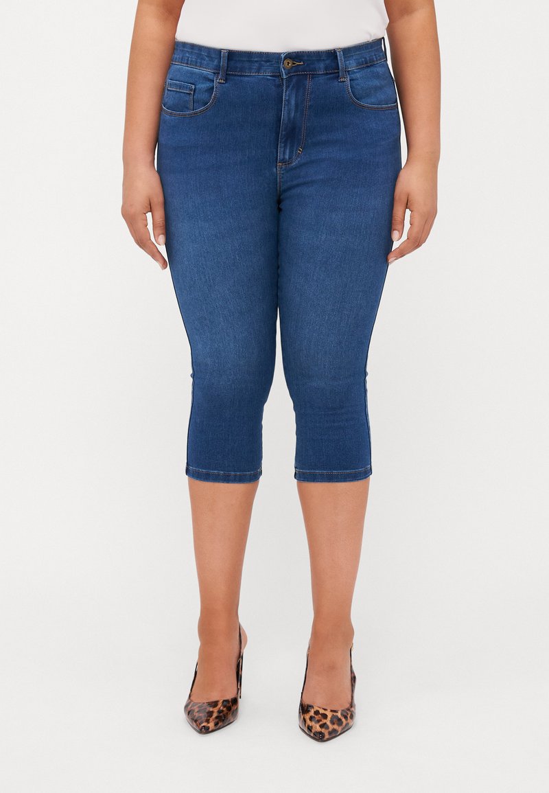 Mørkeblå denim caprijeans med middels høyde i livet, fem lommer og sømdetaljer, som har en tettsittende silhuett og hemmede ermer.
