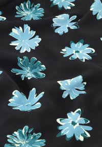 Schwarzer Stoff mit großen blauen Blumenmustern und grünen Akzenten, der eine glatte Textur und einen lebhaften Farbakzent zeigt.