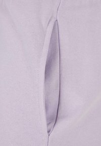 Lys lilla stoff med en glatt tekstur; har en sidelomme med en subtil åpning for tilgang.