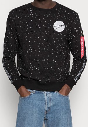 Black sweatshirt with white star pattern, NASA logo on chest, "NASA" text on sleeves, and red "Remove Before Flight" tag on left arm.