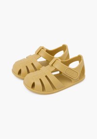 Sandalias amarillas de plástico moldeado con diseño de punta abierta, que cuentan con correas anchas y un cierre de hebilla para un ajuste seguro. Suelas texturizadas.