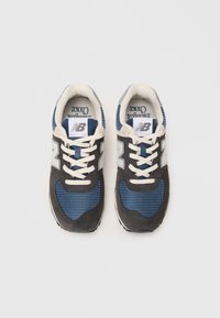 Baskets bleu et gris avec des tiges en maille et en daim, présentant un motif texturé, des lacets crème et un logo New Balance blanc sur le côté.