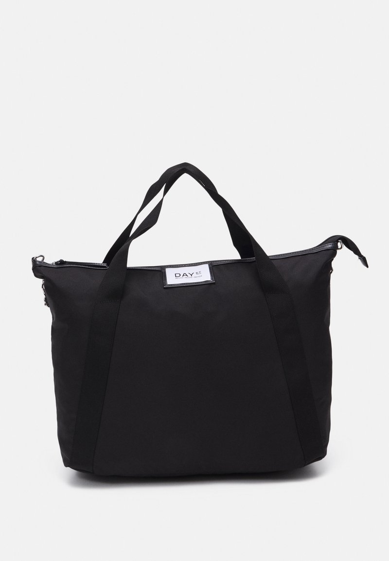 Sac fourre-tout noir en tissu avec deux poignées supérieures, fermeture éclair et forme rectangulaire. Présente une étiquette de logo sur un côté. Matériau texturé.