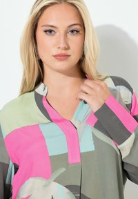 Langærmet bluse i et let, struktureret stof med et patchworkmønster i pink, grøn, grå og blå med en kragefri udforming.