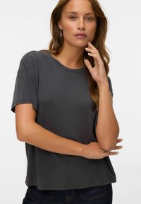 Grå kortærmet t-shirt med rund halsudskæring, blød tekstur, afslappet pasform og minimal syning. Sammen med mørk denim jeans.